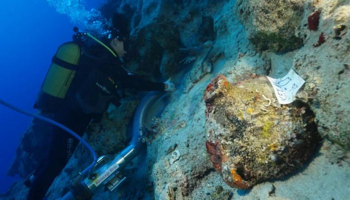 Kekova açıklarındaki batık alanında seramik bir kabı inceleyen dalgıç